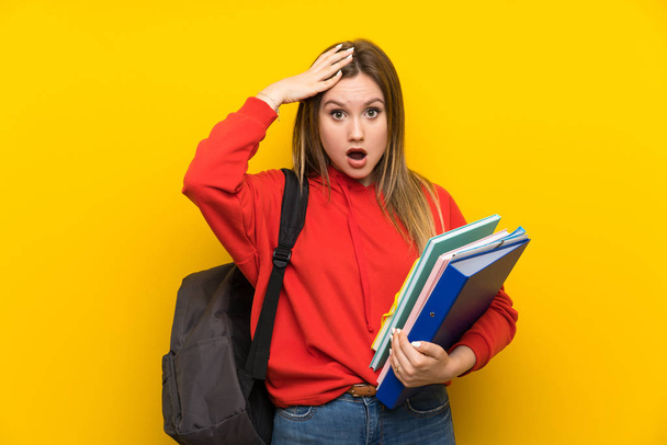 Adolescente estudiante sobre fondo amarillo con la expresión facial sorpresa
 - Foto, Imagen
