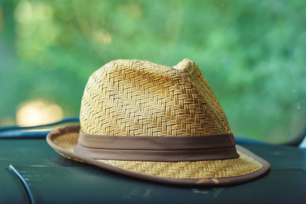 Hasır şapka arabadaki vites panelinde. Yaz yolculuğu. Şapka başlığı. - Fotoğraf, Görsel