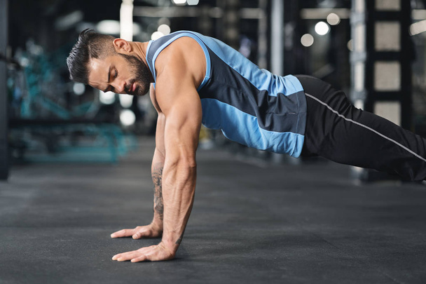 Sporty young man doing pushups in gym - Photo, Image