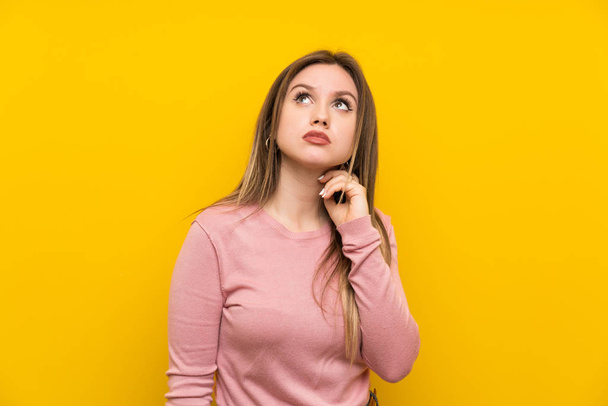 Teenager girl over isolated yellow background thinking an idea - Foto, Bild