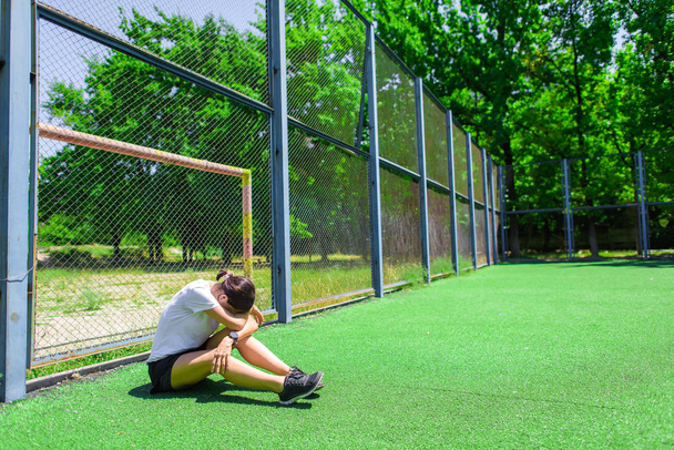 Girl resting after training. Children play with the ball on the Playground. Athlete warming up on the football field. - Φωτογραφία, εικόνα