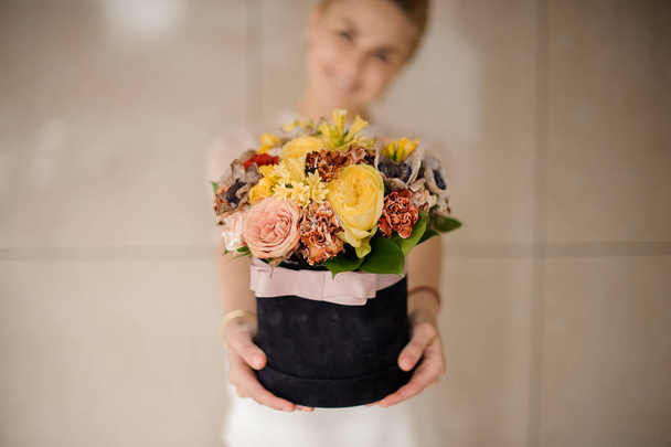 Nő kezében egy fekete bársony doboz sárga és rózsaszín virágok - Fotó, kép