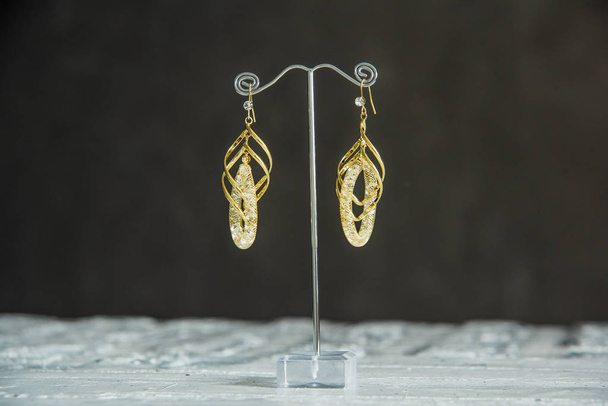 Boucles d'oreilles en or avec pierres précieuses. Ornement de bijoutier. Boucles d'oreilles en or sur le stand
. - Photo, image