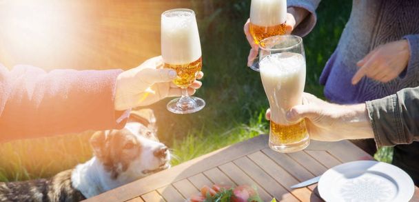 Famille d'âges différents les gens célèbrent joyeusement à l'extérieur avec des verres de bière proclament pain grillé
. - Photo, image