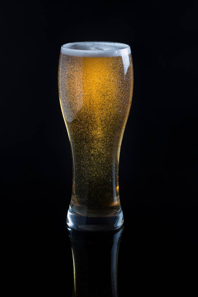 Draft beer in glass on black background - Фото, изображение