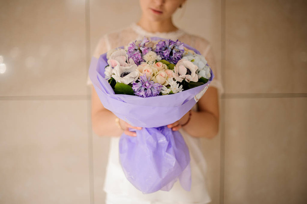 Woman holding a bouquet of tender light color spring flowers - 写真・画像