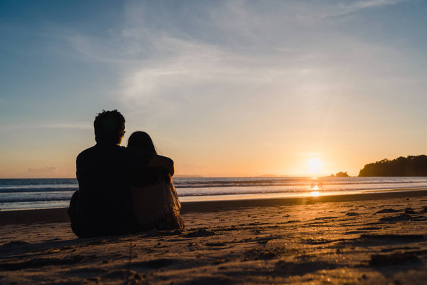 Jeune couple asiatique regardant coucher de soleil près de la plage, couple doux heureux se détendre profiter de l'amour et moment romantique lorsque le coucher de soleil dans la soirée. Mode de vie couple voyage sur la plage concept
. - Photo, image