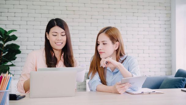 Asiatiques femmes d'affaires en vêtements décontractés intelligents travaillant sur ordinateur portable tout en étant assis sur le bureau sur le bureau
. - Photo, image