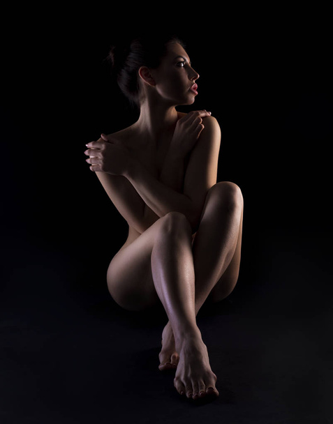 Jeune femme nue avec un corps parfait sur sombre
 - Photo, image