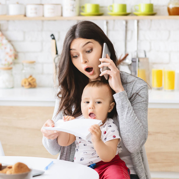 Business mam praten op telefoon en het nemen van notities van baby handen - Foto, afbeelding