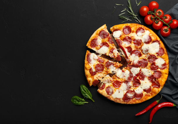 Pizza fresca de pepperoni sobre fondo negro con espacio libre
 - Foto, Imagen