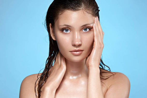 Porträt einer schönen Frau mit nassen Haaren, die vor blauem Hintergrund posiert, Kosmetikkonzept - Foto, Bild