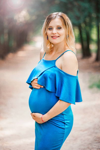 счастливая красивая беременная женщина в синем платье
 - Фото, изображение