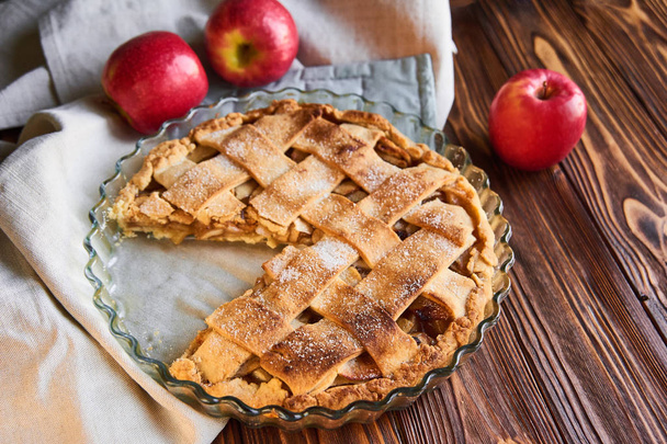 焼き菓子:木製のテーブルの上に白い皿の上に新鮮なリンゴを添えたアップルパイ - 写真・画像