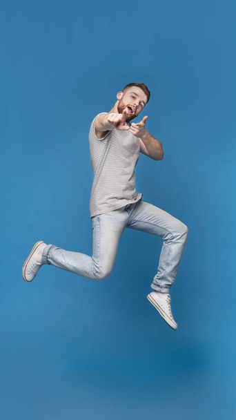 Cheerful man in jumping indicating happily at you - Foto, Imagen