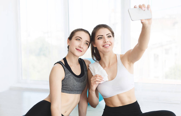 Charming girlfriends making selfie after yoga class - 写真・画像