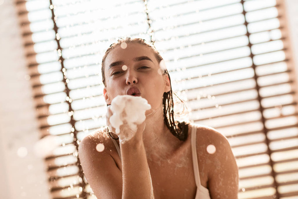 Девушка, дующая мыльные пузыри, принимающая душ дома
 - Фото, изображение