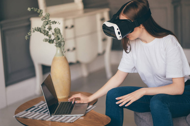 Jonge vrouwelijke programmeur test een nieuwe app met virtual reality glazen in huis - Foto, afbeelding