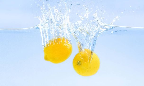 Свежие лимоны тонут в воде с брызгами
 - Фото, изображение