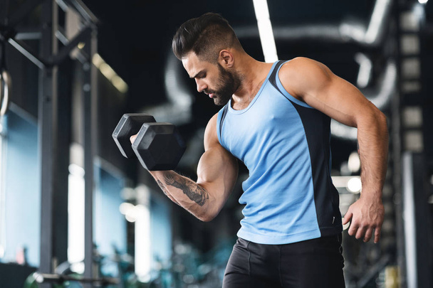 Muscular sportsman with strong body lifting heavy dumbbell - Фото, зображення