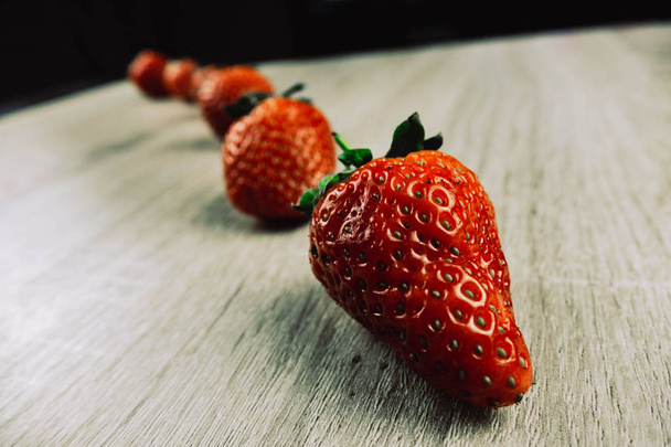 Rijen van rijpe aardbeien op houten oppervlak. Biologische zoete aardbeien in rijen als een seizoensgebonden ontbijt. Vers van de boerderij. - Foto, afbeelding