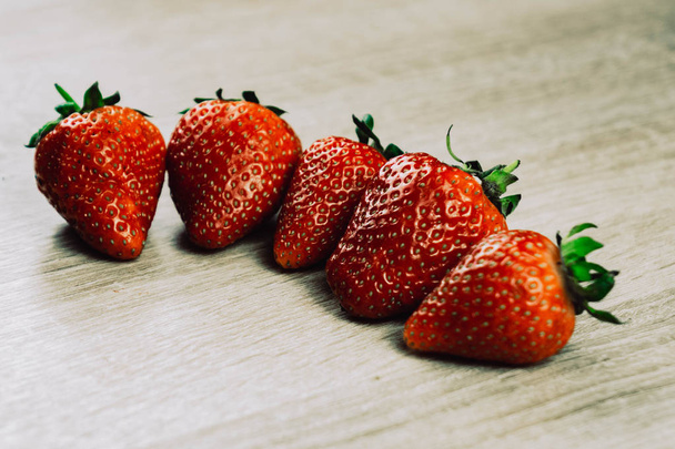 Σειρές από ώριμες φράουλες σε ξύλινη επιφάνεια. Βιολογικά γλυκά φράουλες σε σειρές ως ένα εποχιακό πρωινό. Νωπά από ένα αγρόκτημα. - Φωτογραφία, εικόνα