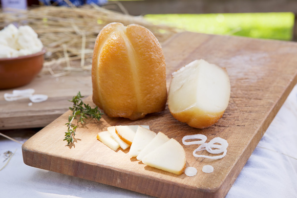Rebanadas de queso ahumado y gran pieza sobre tabla de madera
. - Foto, imagen