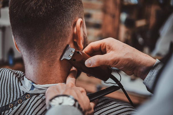 Thendy kapper bij modern Barbershop werkt aan klanten kapsel. - Foto, afbeelding
