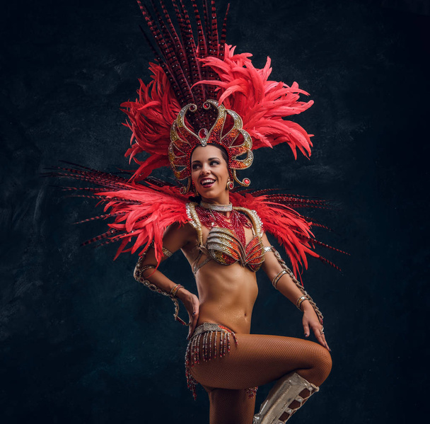 Piękne Brasil tancerz w czerwonym stroju pióro tańczy na małej scenie. - Zdjęcie, obraz