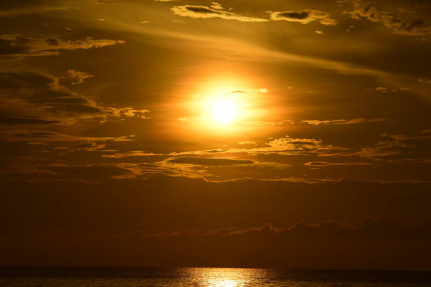 O sol nascente e o céu amarelo dourado na praia junto ao mar no início da manhã
 - Foto, Imagem