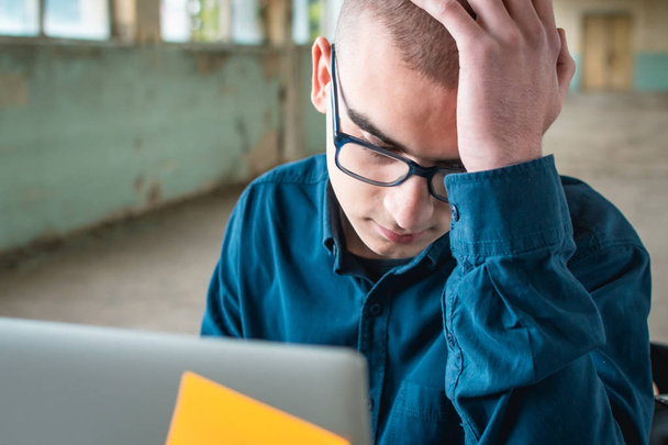 Estudante de camisa azul com um laptop na frente dele, preparando-se para o exame
. - Foto, Imagem
