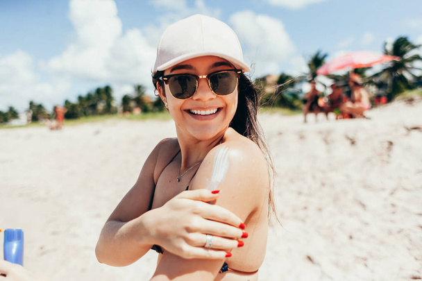 Sunscreen, sunblock. Woman putting solar cream on shoulder smiling beautiful summer day. Skincare. Girl applying sun cream - Foto, Bild