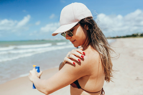 Sunscreen, sunblock. Woman putting solar cream on shoulder smiling beautiful summer day. Skincare. Girl applying sun cream - Foto, afbeelding