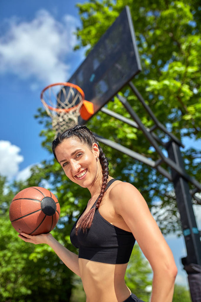 Bella ragazza sexy fitness in nero abbigliamento sportivo con corpo perfetto con palla da basket al campo da basket. Sport, fitness, lifestyle concept
 - Foto, immagini
