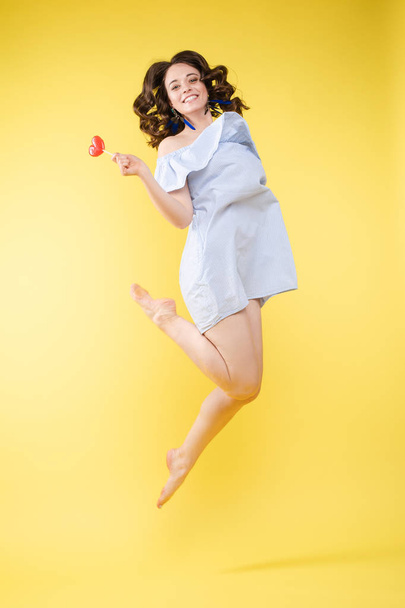 Cheerful brunette young woman in casual outlook jumping in mid air in studio. - Фото, зображення