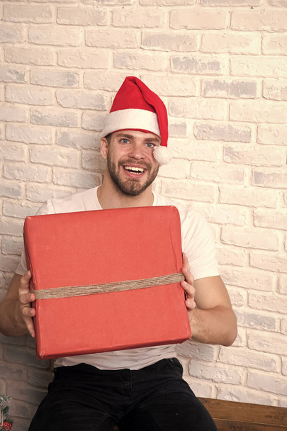 Macho in christmas hat smile with wrapped present - Foto, afbeelding