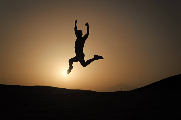 Keep moving. Silhouette man motion jump in front of sunset sky background. Daily motivation. Healthy lifestyle personal achievements goals and success. Future success depends on your efforts now - Fotó, kép