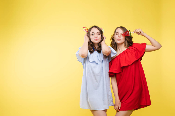 Charming twins closing eyes with lollipops and posing - 写真・画像