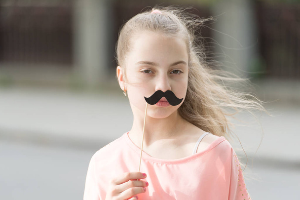 Loving her mustache. Little girl with fake mustache. Cute child holding mustache props on stick. Having fun with photobooth party mustache - Фото, изображение