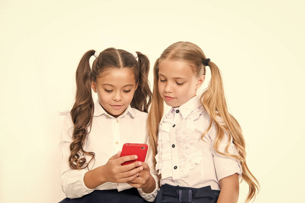Let me show you something interesting. Educational application. Online entertainment concept. Schoolgirls cute pupils use smartphone check social networks. Send message friend. Online communication - 写真・画像