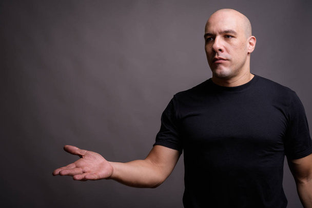 Portrait of handsome bald man against gray background - Foto, afbeelding