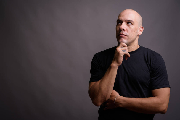 Portrait of handsome bald man against gray background - Foto, imagen