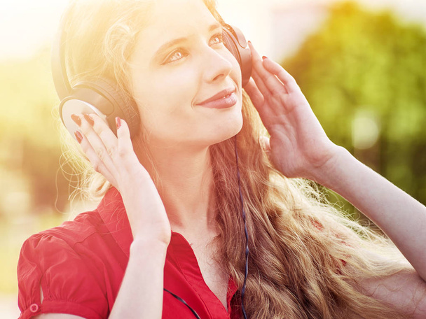 Chica en auriculares y camisa roja escucha música mp3
 - Foto, Imagen