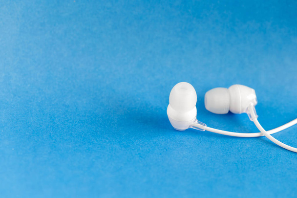 White earbuds on blue colorful background with copy space for text - Foto, Imagen