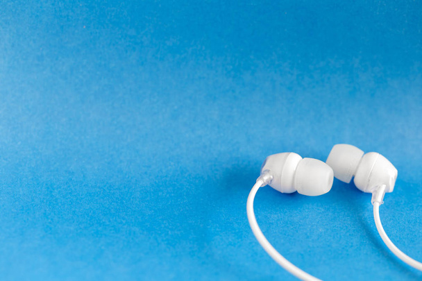 White earbuds on blue colorful background with copy space for text - Photo, Image