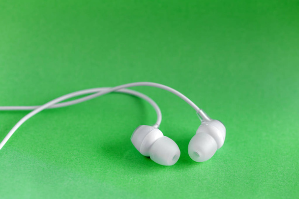 White earbuds on green colorful background with copy space for text - Photo, Image