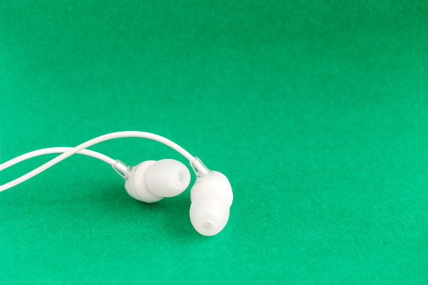 White earbuds on green colorful background with copy space for text - Photo, Image