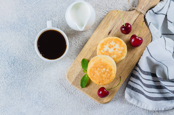 Sommerfrühstück mit Quark-Pfannkuchen, Tasse schwarzen Kaffee, Milch auf weißem Tischhintergrund. Ansicht von oben - Foto, Bild