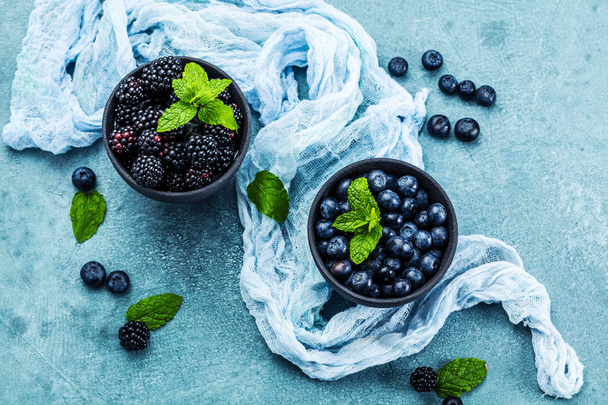 top view of fresh ripe blackberries and blueberries in bowls - 写真・画像