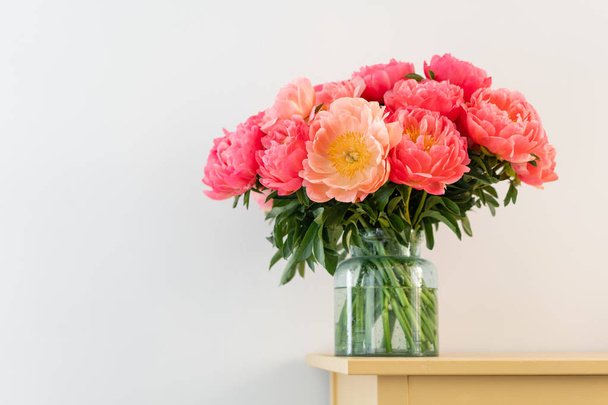 Korall-pünkösdi rózsa üvegvázában fából készült asztal.. Gyönyörű pünkösdi rózsa virág a katalógus vagy online áruház. Floral Shop koncepció. Gyönyörű friss vágott csokor. Virágok szállítás. Lemezterület másolása - Fotó, kép